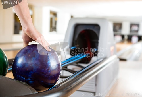 Image of Man's Hand Picking Up Bowling Ball From Rack