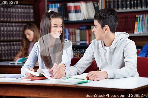 Image of Teenage Couple Holding Hands At Table In Library