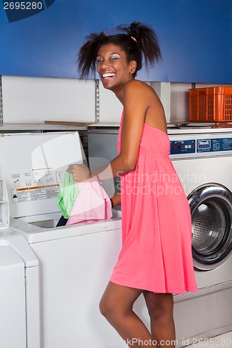 Image of Woman Putting Clothes In Washing Machine