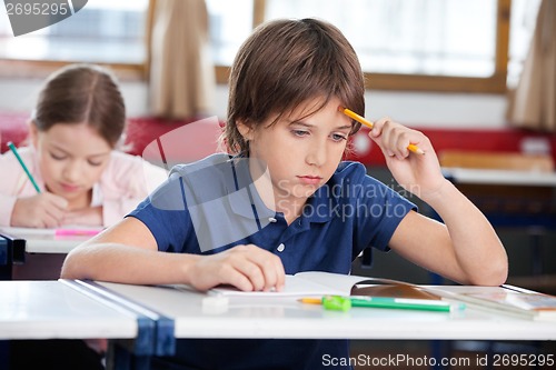 Image of Thoughtful Schoolboy Sitting At Desk