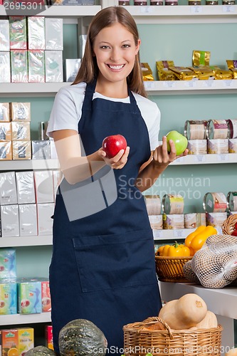 Image of Saleswoman Holding Apples In Supermarket