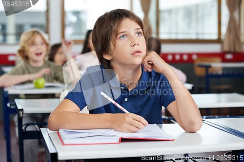 Image of Boy Looking Up While Writing At Desk