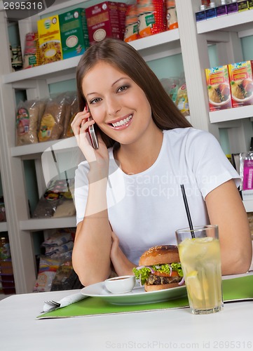 Image of Woman Using Phone While Having Snacks In Store