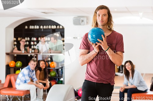 Image of Confident Man Holding Bowling Ball in Club