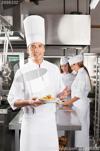 Image of Confident Chef Presenting Dish In Commercial Kitchen