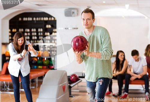 Image of Man Bowling With Friend Photographing in Club