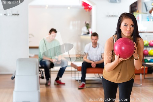 Image of Young Woman Holding Bowling Ball in Club