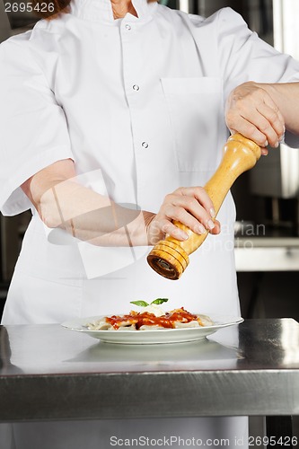 Image of Female Chef Seasoning Dish With Pepper