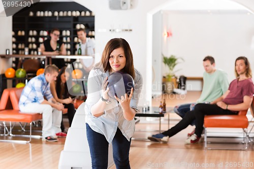 Image of Young Woman Bowling in Club