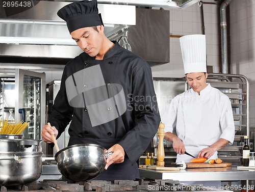 Image of Chef Cooking Food With Colleague Chopping Vegetable