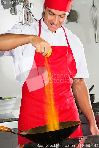 Image of Chef Adding Turmeric Powder In Pan