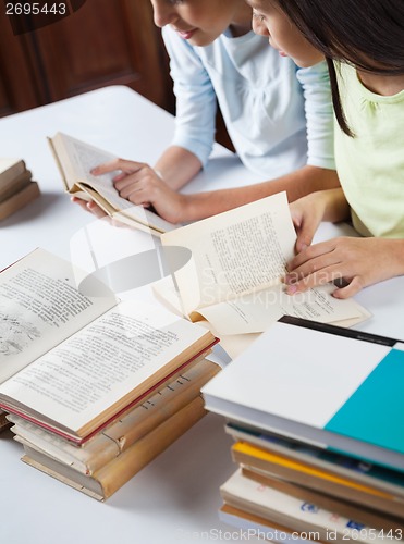 Image of Schoolgirls Reading Books At Table In Library