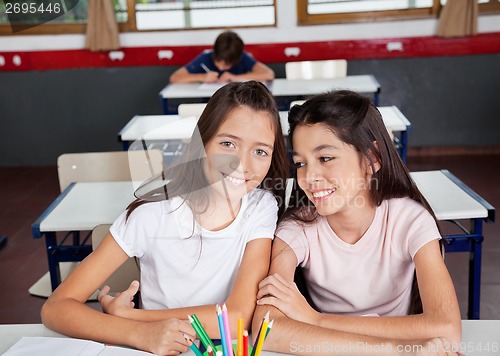 Image of Schoolgirl Sitting With Female Friend In Classroom