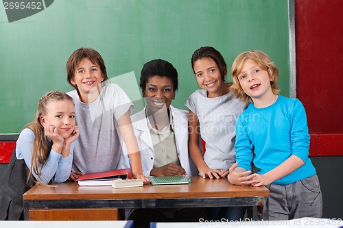 Image of Happy Teacher With Students At Desk