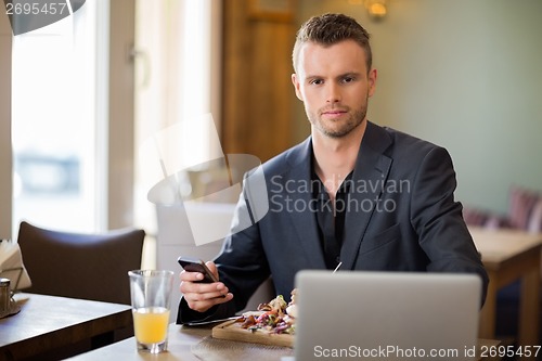 Image of Young Business man With Mobilephone And Laptop In Coffeeshop