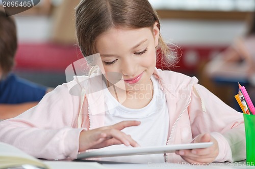 Image of Schoolgirl Smiling While Using Tablet At Desk