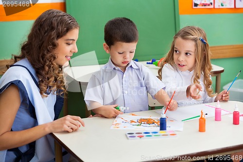 Image of Teacher With Children Painting At Desk