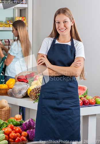 Image of Saleswoman Standing Arms Crossed With Woman Shopping In Backgrou