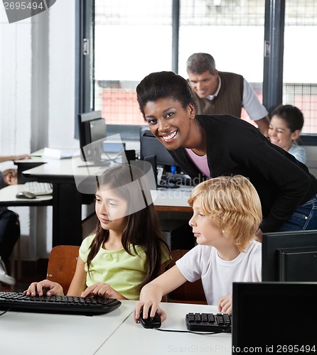 Image of Female Teacher With Students At Desk