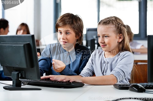 Image of Boy Pointing While Using Desktop Pc With Friend At Desk