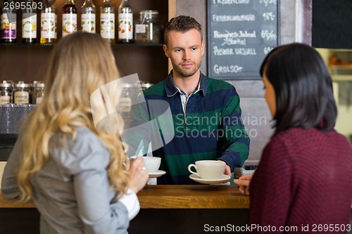 Image of Bartender Serving Coffee To Women At Counter In Cafe