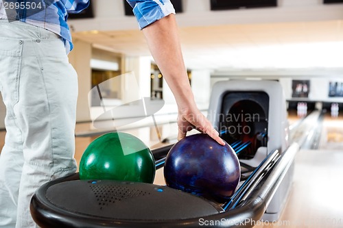 Image of Man's Hand Picking Up Bowling Ball From Rack