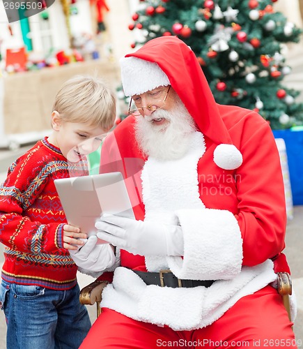 Image of Boy And Santa Claus Using Digital Tablet