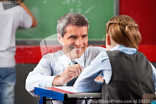 Image of Teacher Looking At Schoolgirl Sitting At Desk
