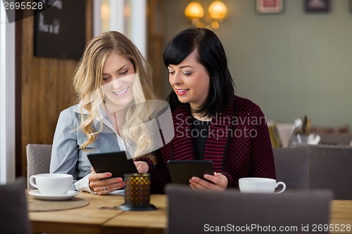 Image of Female Friends With Digital Tablets At Coffeeshop