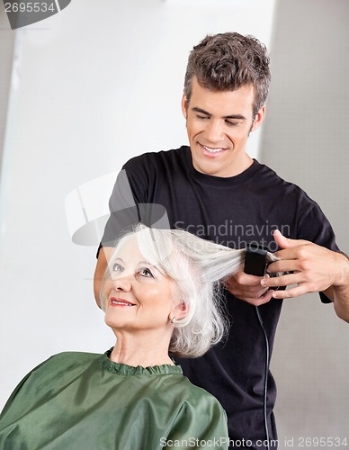 Image of Hairstylist Straightening Senior Woman's Hair