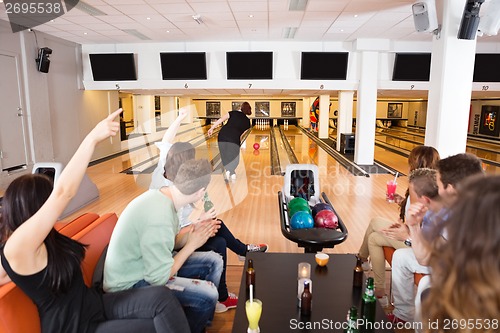 Image of Friends Cheering Woman Bowling in Club