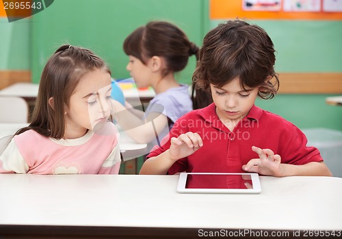 Image of Boy Using Digital Tablet With Friend At Desk