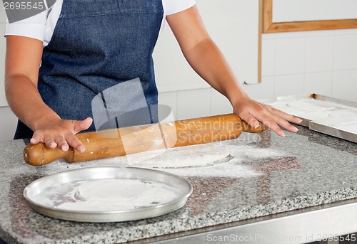 Image of Female Chef Rolling Dough On Counter