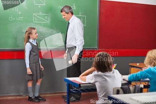 Image of Teacher And Girl Discussing Lesson In Classroom