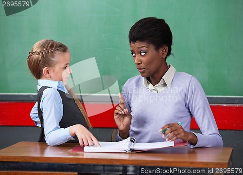 Image of Female Teacher Scolding Schoolgirl At Desk