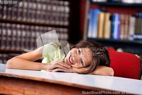 Image of Happy Schoolgirl Looking Away While Leaning On Table