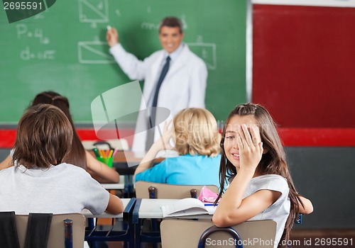 Image of Girl Covering One Eye While Sitting At Desk