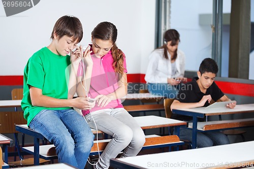 Image of Teenage Schoolchildren Listening Music In Classroom