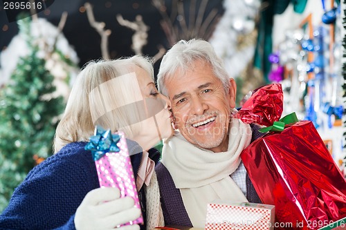 Image of Senior Woman Kissing Man With Christmas Presents