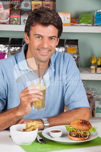 Image of Man With Drink And Burger In Supermarket