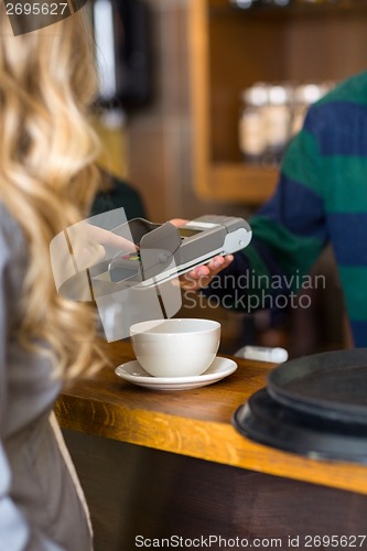 Image of Young Woman Entering Pin In Card-reader