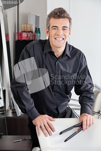 Image of Happy Hairstylist Holding Straightener