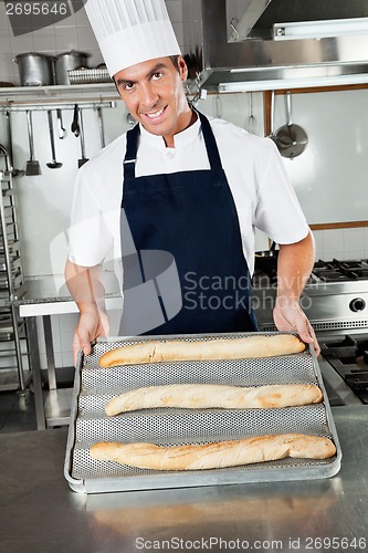Image of Male Chef Presenting Baked Loafs In Kitchen