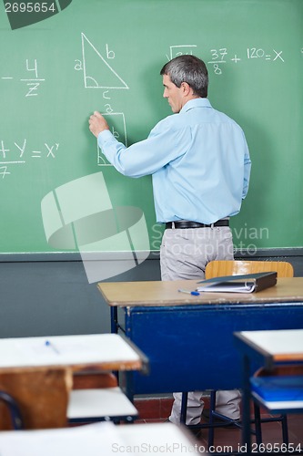 Image of Professor Solving Mathematics On Greenboard In Classroom