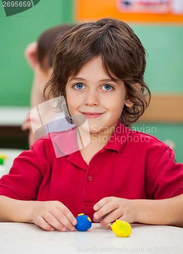 Image of Little Boy With Clay At Desk