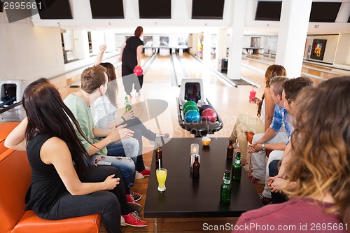 Image of Friends Looking At Woman Bowling in Club