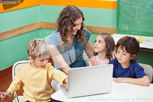 Image of Children Using Laptop While Teacher Assisting Them