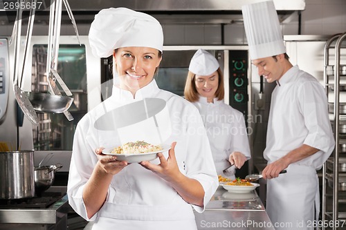 Image of Happy Chef Presenting Dish In Industrial Kitchen