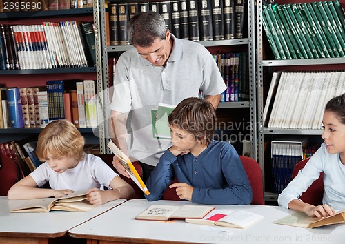 Image of Male Librarian Showing Book To Schoolboy