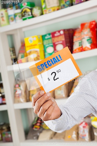 Image of Male Owner Holding Discount Sign In Supermarket